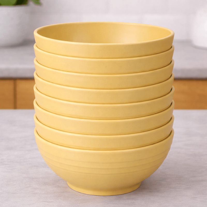 Stack of yellow wheat straw bowls on a neutral background