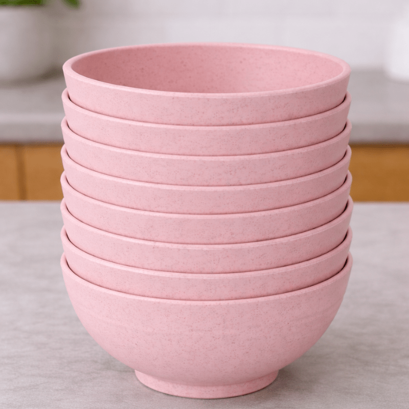 Stack of pink wheat straw bowls on a neutral background