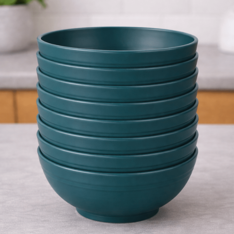 Stack of dark green straw bowls on a neutral background